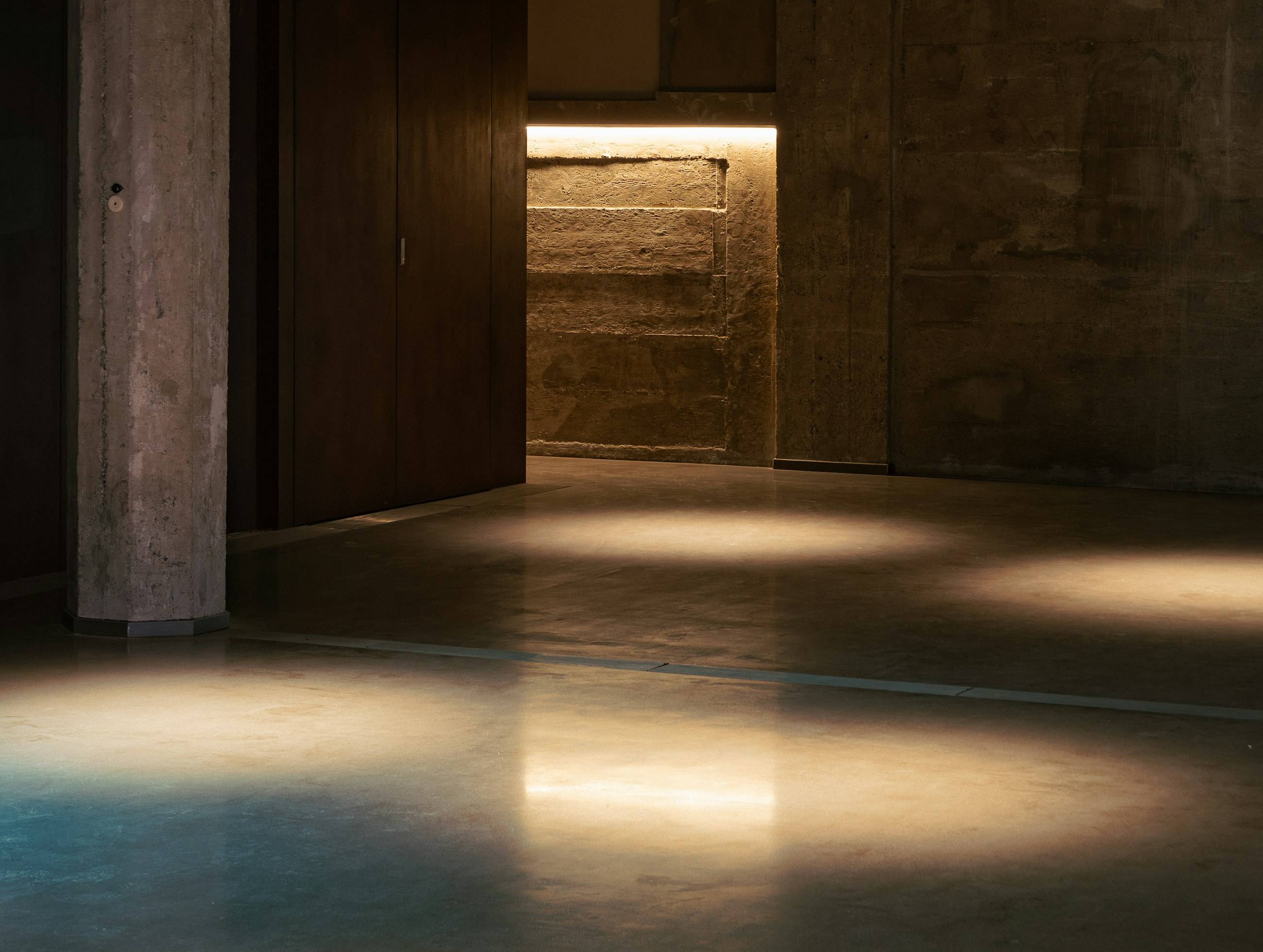 Ambiente de concreto iluminado pela luz de uma porta aberta
